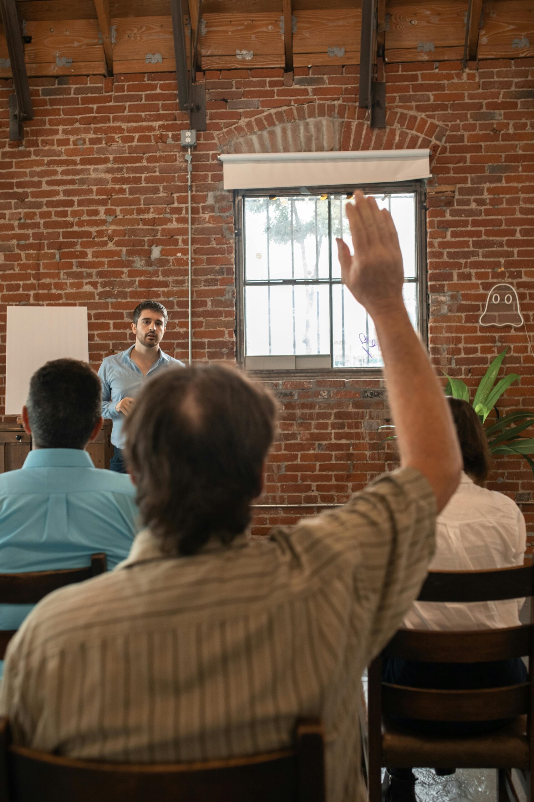 Adults engaged in a classroom workshop, one raises hand to participate.